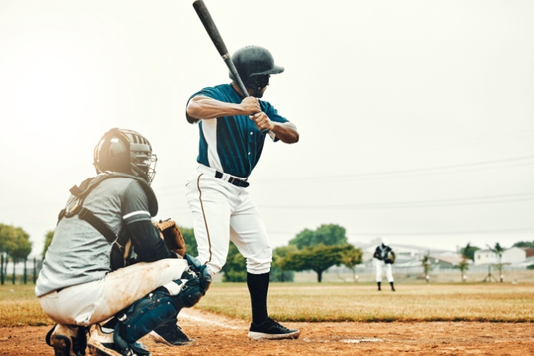 a baseball player stands at bat with the catcher kneeling behind him
