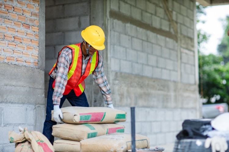 a construction worker moves bags of cement at a worksite